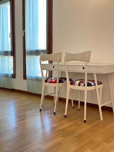 two chairs sitting next to a desk and a table at Appartamento Marisa in San Vendemiano
