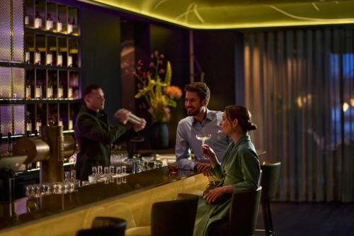 a man and a woman sitting at a bar at Koenigshof, a Luxury Collection Hotel, Munich in Munich
