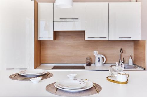 une cuisine avec des placards blancs et des assiettes sur un comptoir dans l'établissement GreenHill Scenic Apartment, à Gornji Orahovac