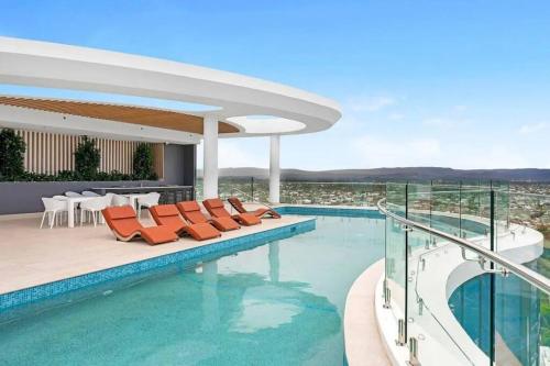 a swimming pool with orange chairs in a building at Coastal Escape in Broadbeach in Gold Coast