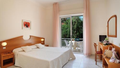 a bedroom with a bed and a window and a table at Hotel Helios in Diano Marina