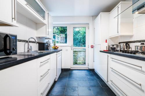 a kitchen with white cabinets and a blue tile floor at Mayflower 5-Bed Home, Contractors, Family, Harry Porter in Hemel Hempstead
