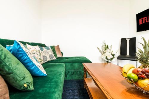 a living room with a green couch and a table with a bowl of fruit at Mayflower 5-Bed Home, Contractors, Family, Harry Porter in Hemel Hempstead