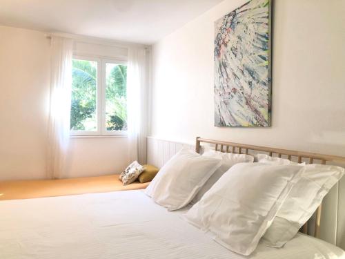 a bedroom with a bed with white pillows and a window at L’appartement - Jardin Secret in Marseille
