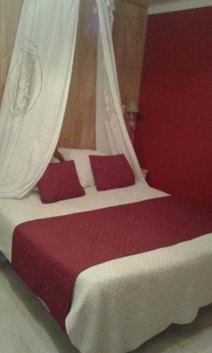 a bedroom with a large bed with red and white pillows at Hôtel-Restaurant Le Rouffillac in Carlux