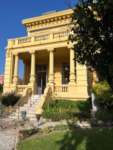 un grand bâtiment jaune avec des escaliers en face de celui-ci dans l'établissement Appartement exceptionnel belle époque avec grande terrasse plein sud, à Nice
