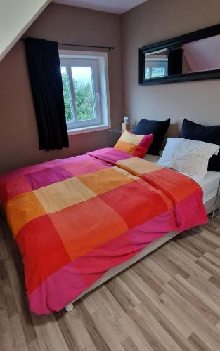 a large bed with a colorful comforter in a bedroom at Haus Soltun-Was will man mehr! in Runde