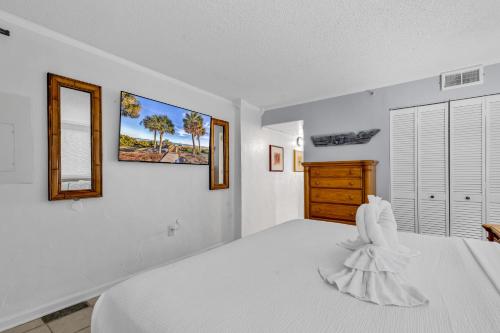 a white bedroom with a bed and two mirrors at Spectacular Oceanview Condos in Myrtle Beach