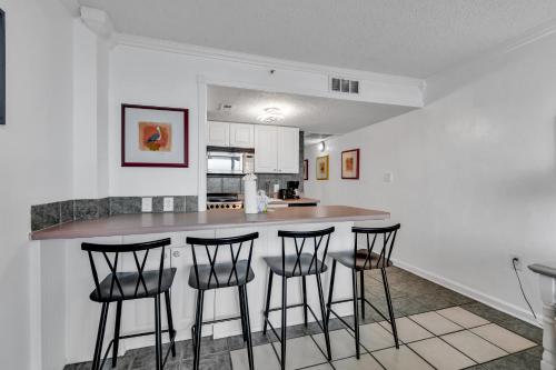 a kitchen with a bar with four stools in it at Spectacular Oceanview Condos in Myrtle Beach