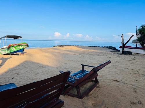 a bench sitting on a beach with a boat at Omeesha Beach Hotel in Kalpitiya