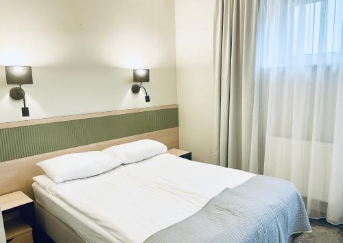 a bedroom with a bed with two pillows and a window at Hotel z Sanatorium Uzdrowiskowym Knieja Spa&Wellness in Supraśl