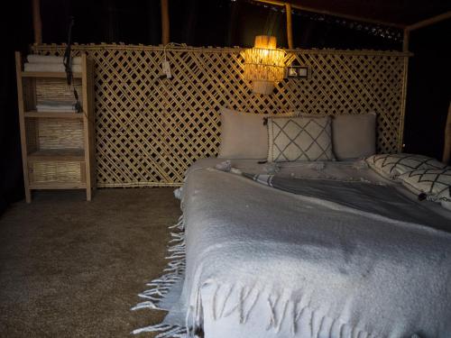 a bedroom with a large bed with a light on it at Berber Beldi Camp in Imsouane