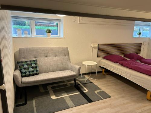 a bedroom with a chair and a bed and window at H. C. Lumbyes Vej - kælderlejlighed in Odense