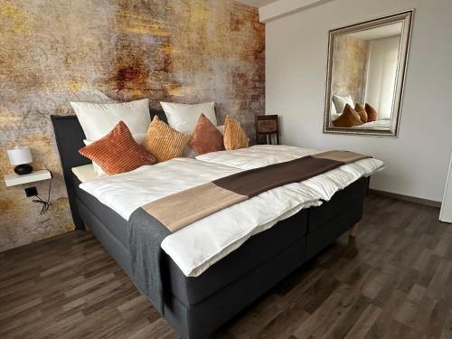 a bedroom with a large bed with orange and white pillows at Ferienwohnung Forstblick in Kranenburg