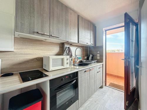 une cuisine avec un micro-ondes et une cuisinière four supérieur dans l'établissement Studio Bord de Mer Boulouris à Saint Raphaël, à Saint-Raphaël