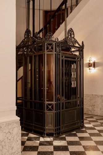 a black gate in a room with a checkered floor at De Gulden Poorte, a LXRYHOME Hotel Collection in Antwerp