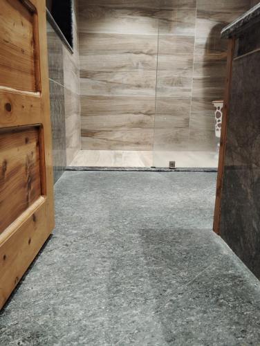 a bathroom with a shower with a wooden door at Hotel CM Palace - Pure Vegetarian in Ner Chowk