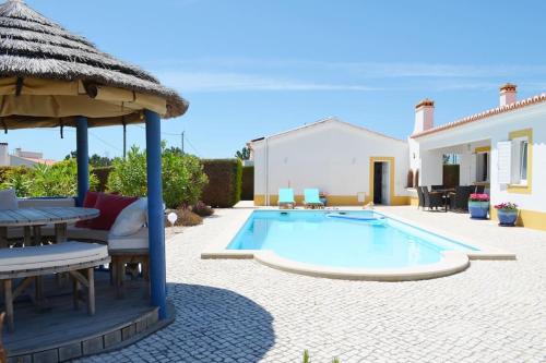 a swimming pool with a table and an umbrella at Wanderlust - Beautiful Villa in Aljezur in Aljezur