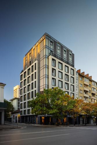 a tall white building with a tree in front of it at B1 Downtown Hotel in Sofia