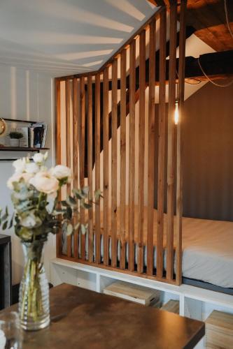 un vase de fleurs sur une table à côté d'un lit dans l'établissement -Les Petits Ga!llards- 3 Studios à Thèmes, à Brive-la-Gaillarde