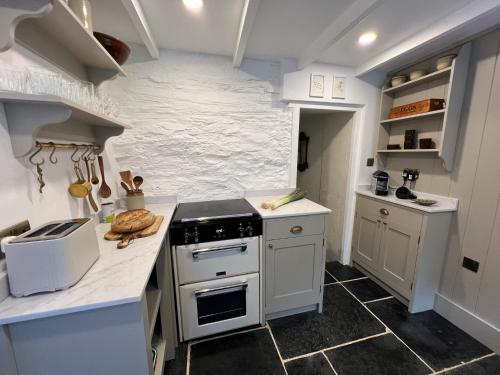 a kitchen with white counters and a stove top oven at Rosebank Cottage in Boscastle