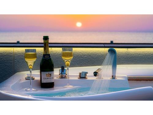 a hot tub with two glasses of wine and a bottle of champagne at OCEAN FRONT TATEYAMA - Vacation STAY 35718v in Tateyama