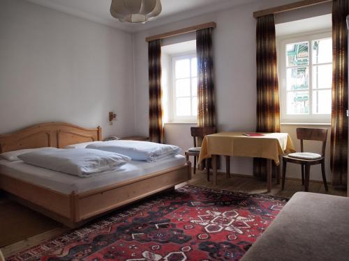a bedroom with a bed and a table and windows at Hotel Bachmann in Villabassa