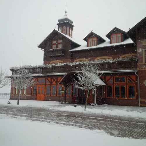a large building with a clock tower in the snow at Berg-Gasthof Honigbrunnen in Löbau