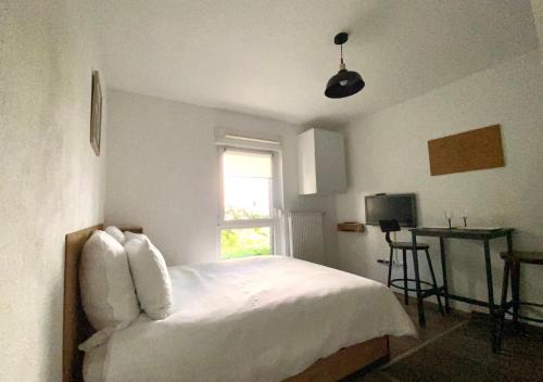 une chambre avec un lit avec des draps blancs et une fenêtre dans l'établissement Studio tout confort au calme proche centre ville, à Strasbourg