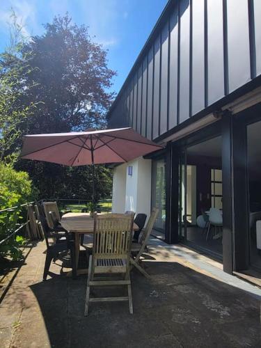 a table and chairs with an umbrella on a patio at Au vert chez Diane in Sparsbach