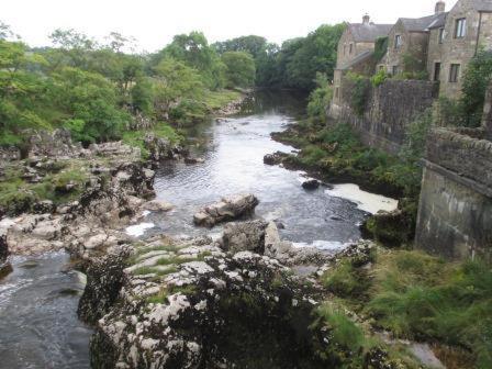 a view of a river with rocks and buildings at Bridge House B & B Grassington in Grassington