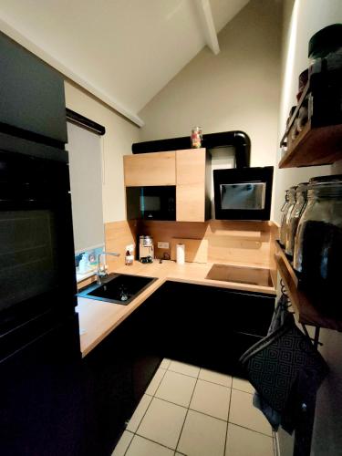 a small kitchen with a sink and a microwave at Maison Aunais in Mormont-La-Grande