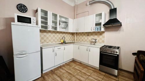 eine Küche mit weißen Schränken und einem weißen Kühlschrank in der Unterkunft Kyiv Khreschatyk 27 Apartment in Kiew
