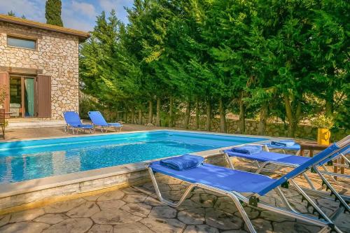 ein Pool mit blauen Stühlen und ein Haus in der Unterkunft Villa Acqua, a luxury villa with private pool, 10 mins drive from the beach in Marantochori