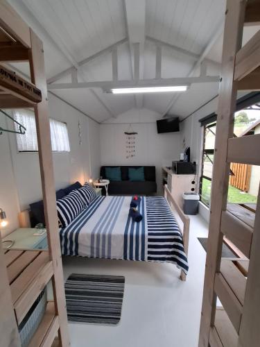 a bedroom with a bed and a couch in a room at Petite Cottage Plett in Plettenberg Bay