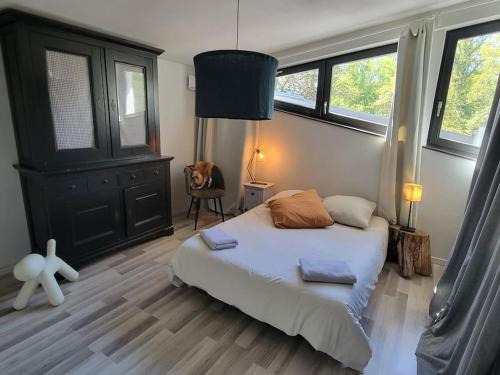 a bedroom with a bed and a chair and windows at Au vert chez Diane in Sparsbach
