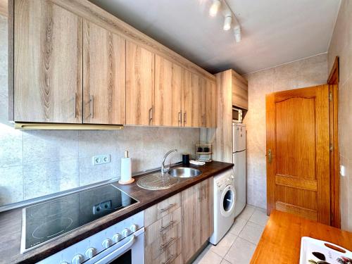 a kitchen with wooden cabinets and a sink at Apartamentos J&K in Torremolinos