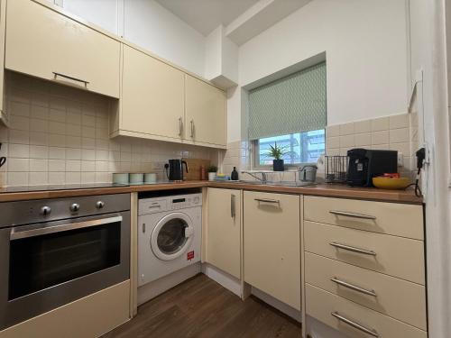 a kitchen with a washing machine and a washer at Vibrant cosy 2 Bedroom Apartment in Coventry