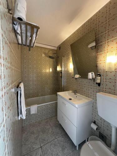 a bathroom with a sink and a toilet and a tub at Hotel Boavista - Vintage House in Monfortinho