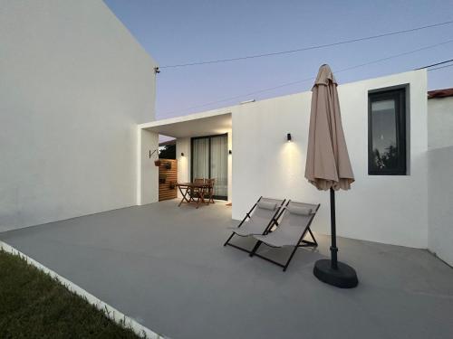 a patio with two chairs and an umbrella at Verde'Água Studio in Mosteiros