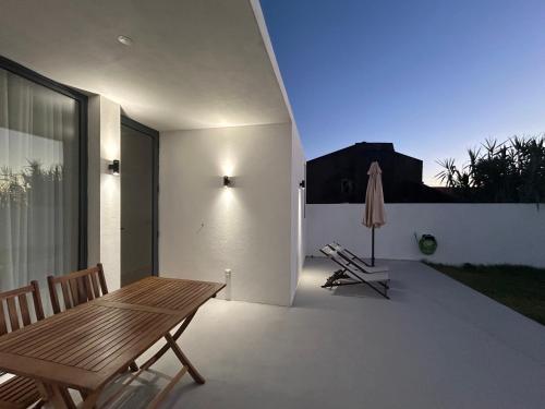 a patio with a wooden table and a umbrella at Verde'Água Studio in Mosteiros