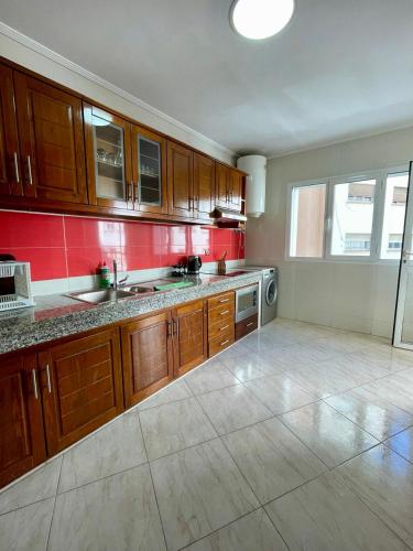 a large kitchen with wooden cabinets and red walls at Appart Hotel Rania in Tangier