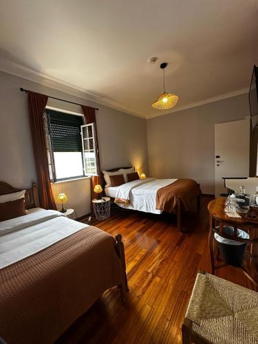 a hotel room with two beds and a table at Hotel Boavista - Vintage House in Monfortinho