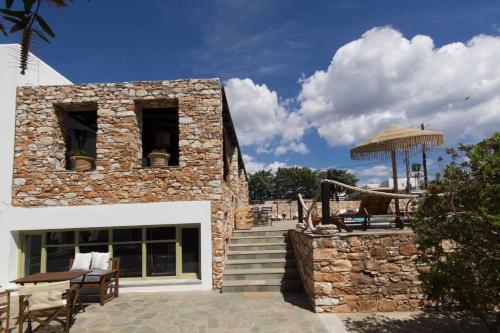 a stone building with a patio with a table and chairs at Parosland Hotel in Aliki