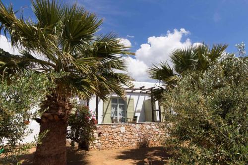 a white house with palm trees in front of it at Parosland Hotel in Aliki