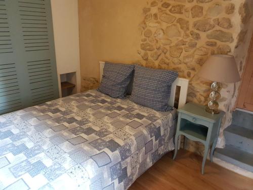 une chambre avec un lit et un mur en pierre dans l'établissement Maison de village avec piscine proche de Narbonne, à Moussan