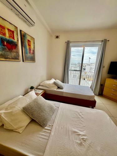 two beds in a room with a window at Double room 5min to Paceville in Is-Swieqi