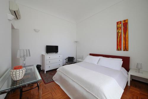 um quarto com uma cama branca e uma mesa de vidro em B&B Five Rooms em Siracusa