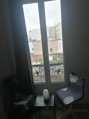 une chambre avec deux chaises et une fenêtre avec vue dans l'établissement Appartement F2 Paris la villette 4 chemins, à Aubervilliers