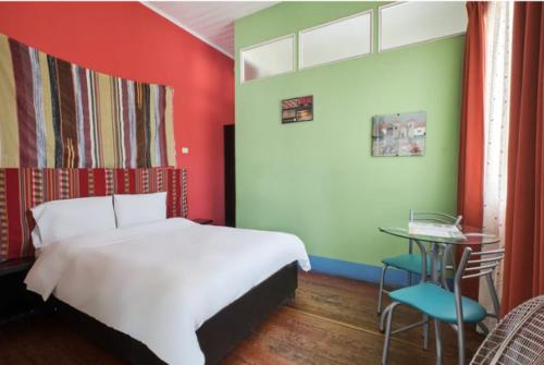 a bedroom with a white bed and a small table at La Casa de Algodon in Huacho